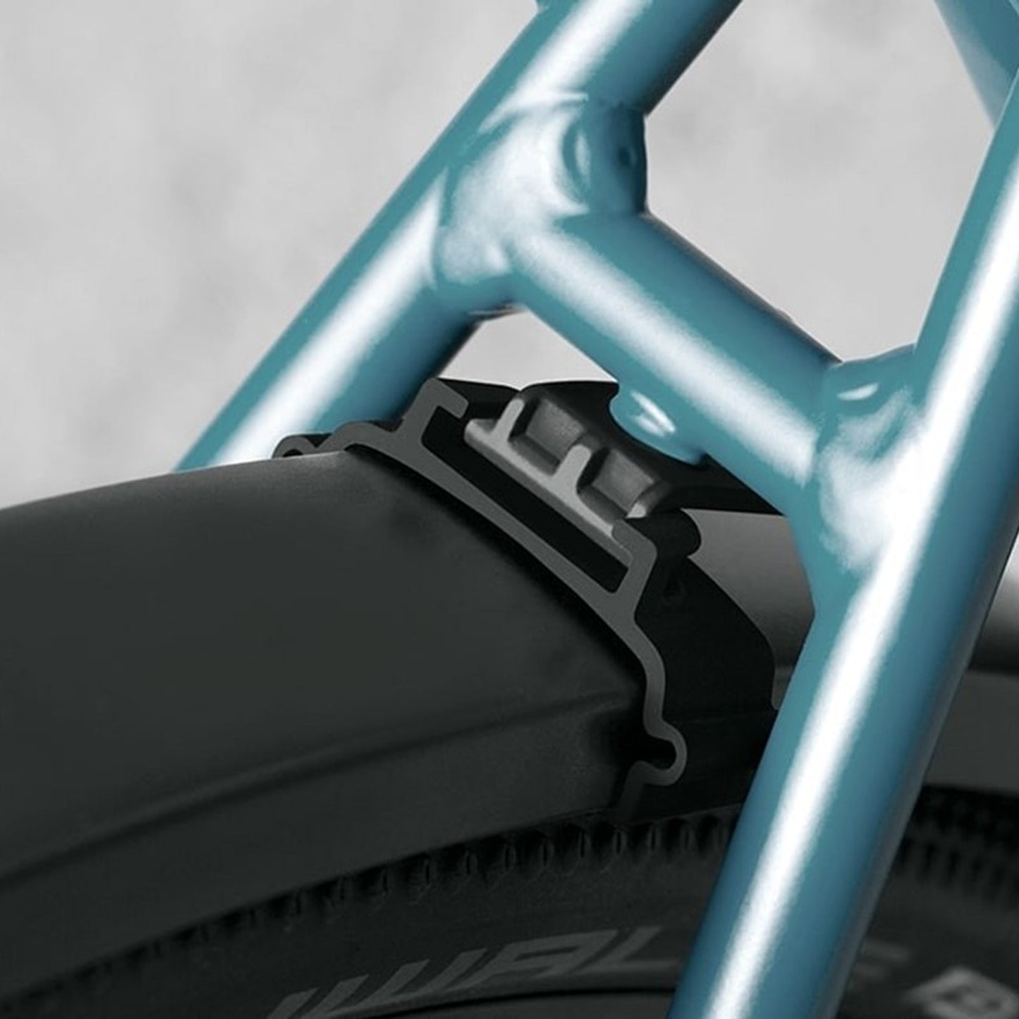 Skärmsatsdetalj: svart fäste och klämma mot blå cykelram