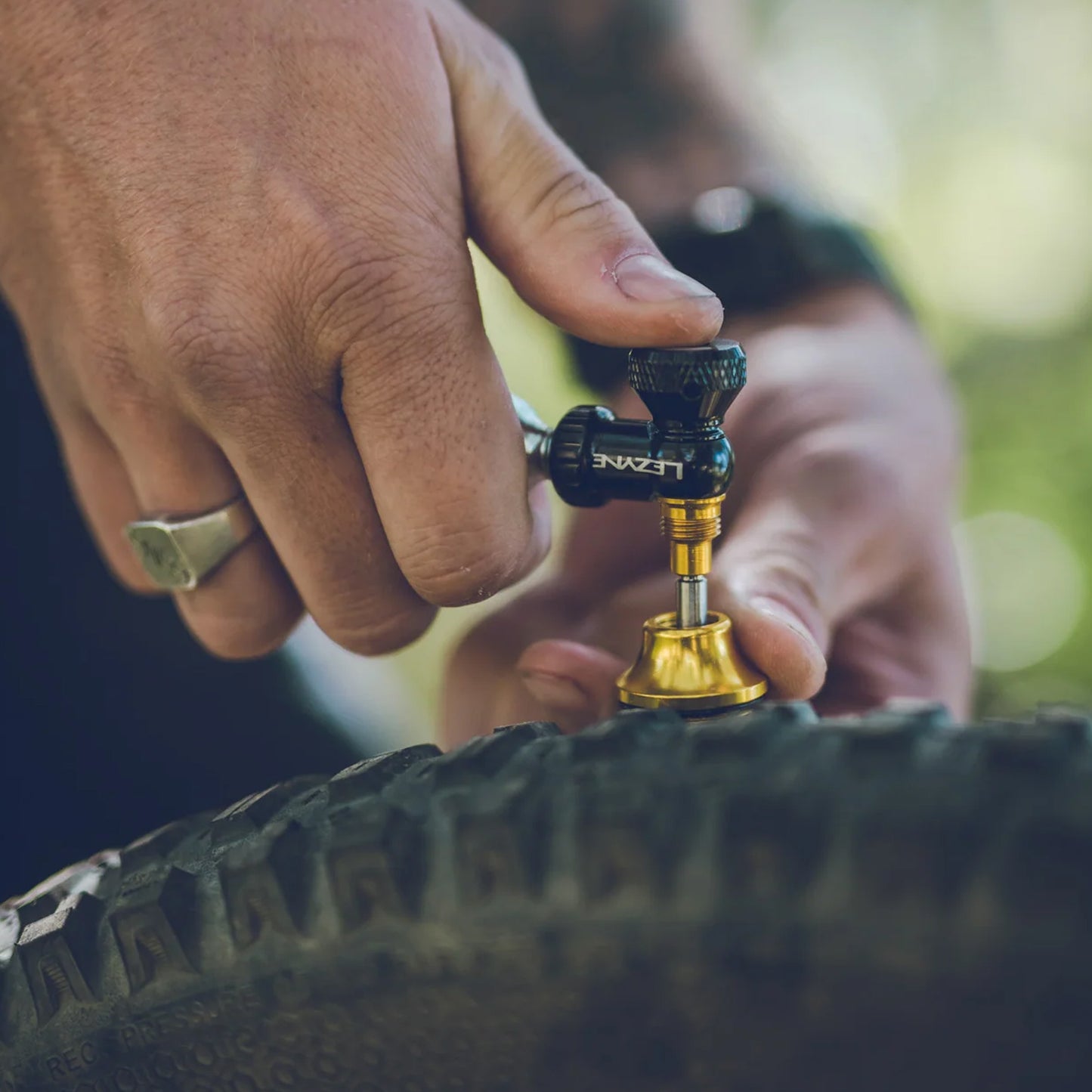 Hand monterar tubeless CO2-blåsare på däckets ventil, mässingsventil synlig