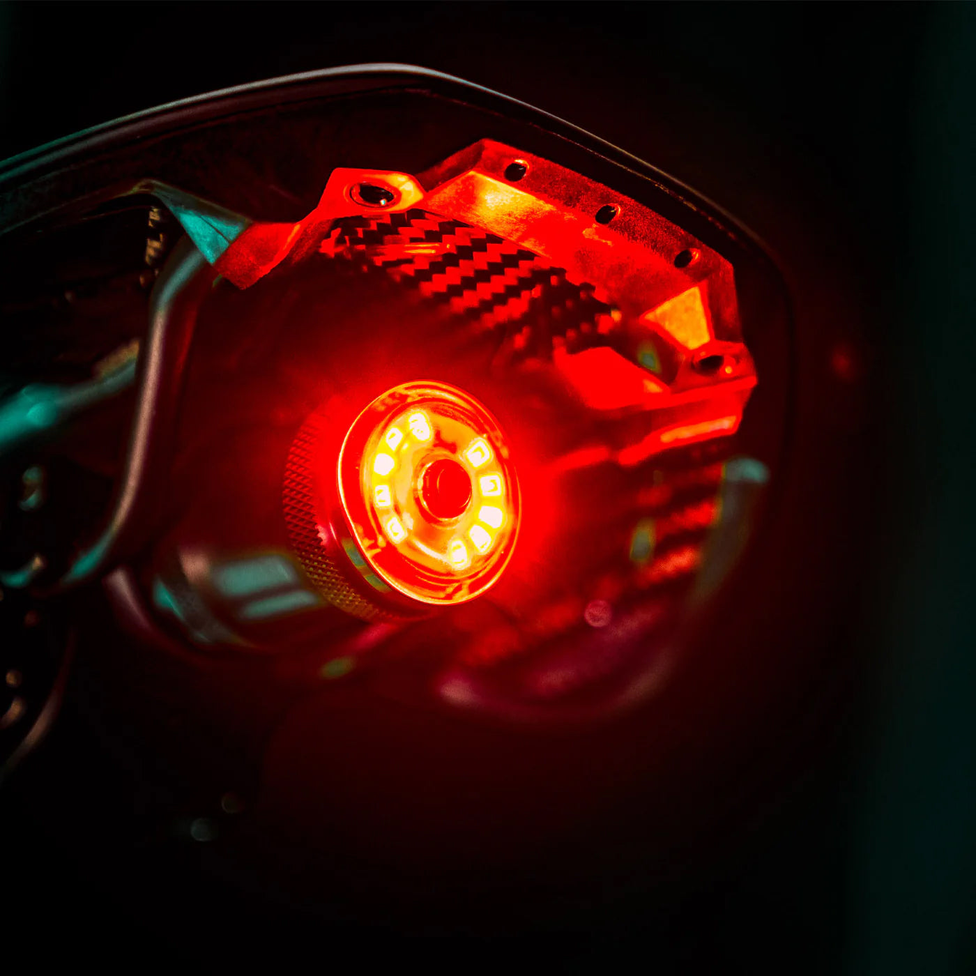 Baklampa Lezyne Saddle Drive 250 tänd i närbild, röd lins och orange diodljus.