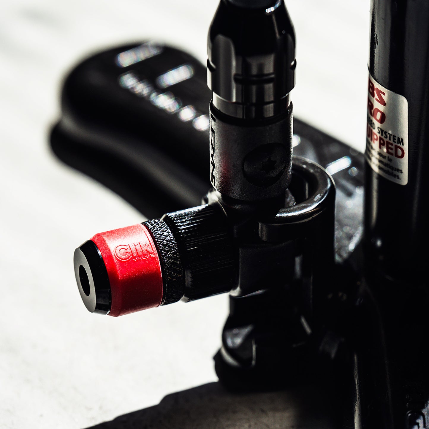 Lezyne Clik™ chuckpumpadapter i röd och svart med gängad anslutning och öppning.