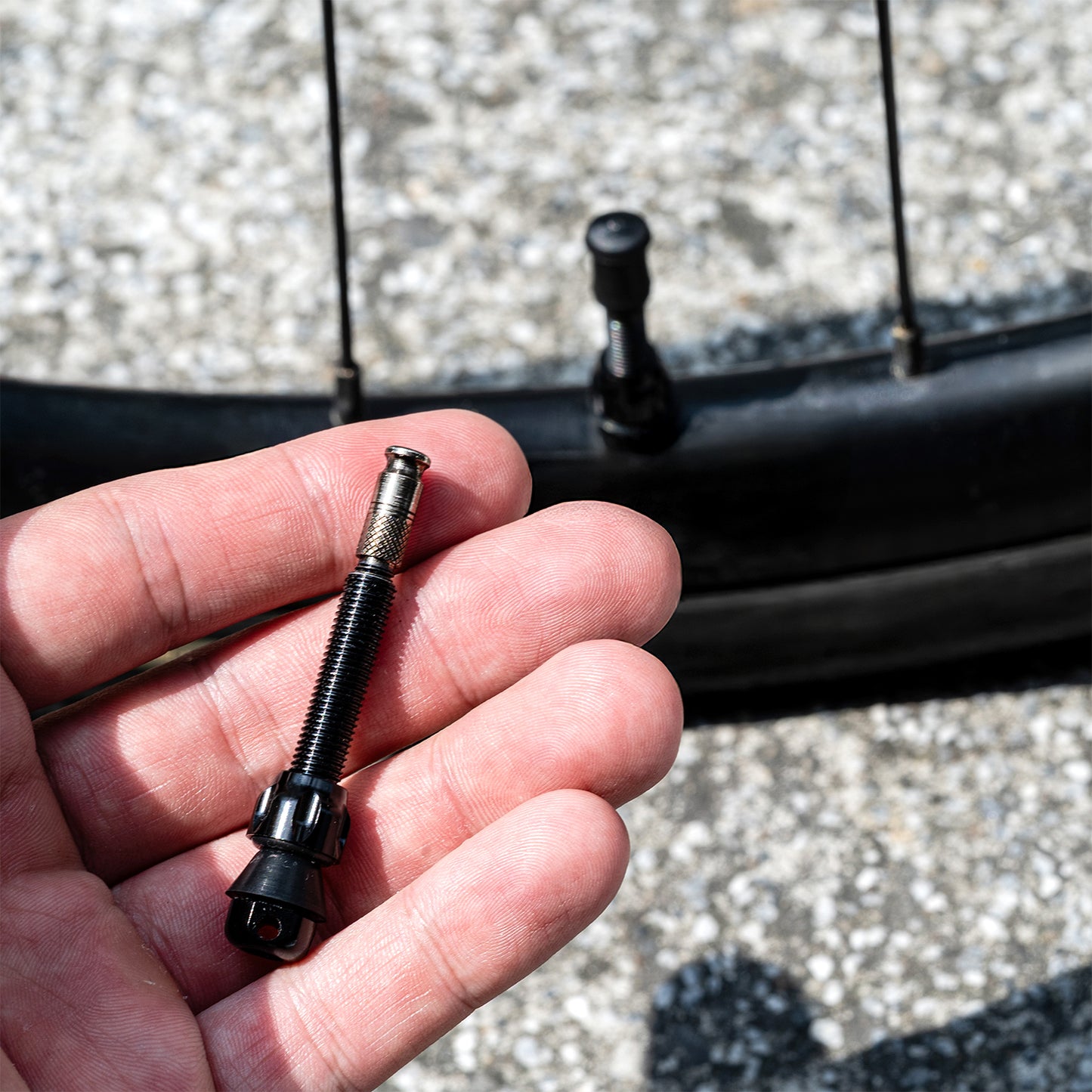 Cykelventil 44 mm i metall och svart, synlig i hand nära däck