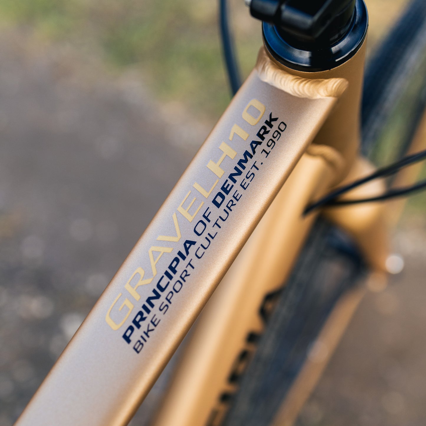 Principia Gravel H10-ramrör med logotyp och text, kopparfärgad ram, detalj.