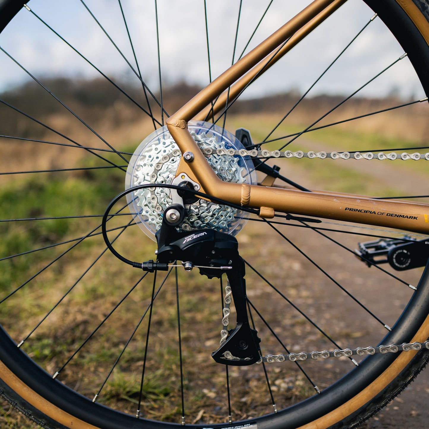 Kopparfärgad gravelcykel med skivbroms och grusdäck på framhjulet, detalj.