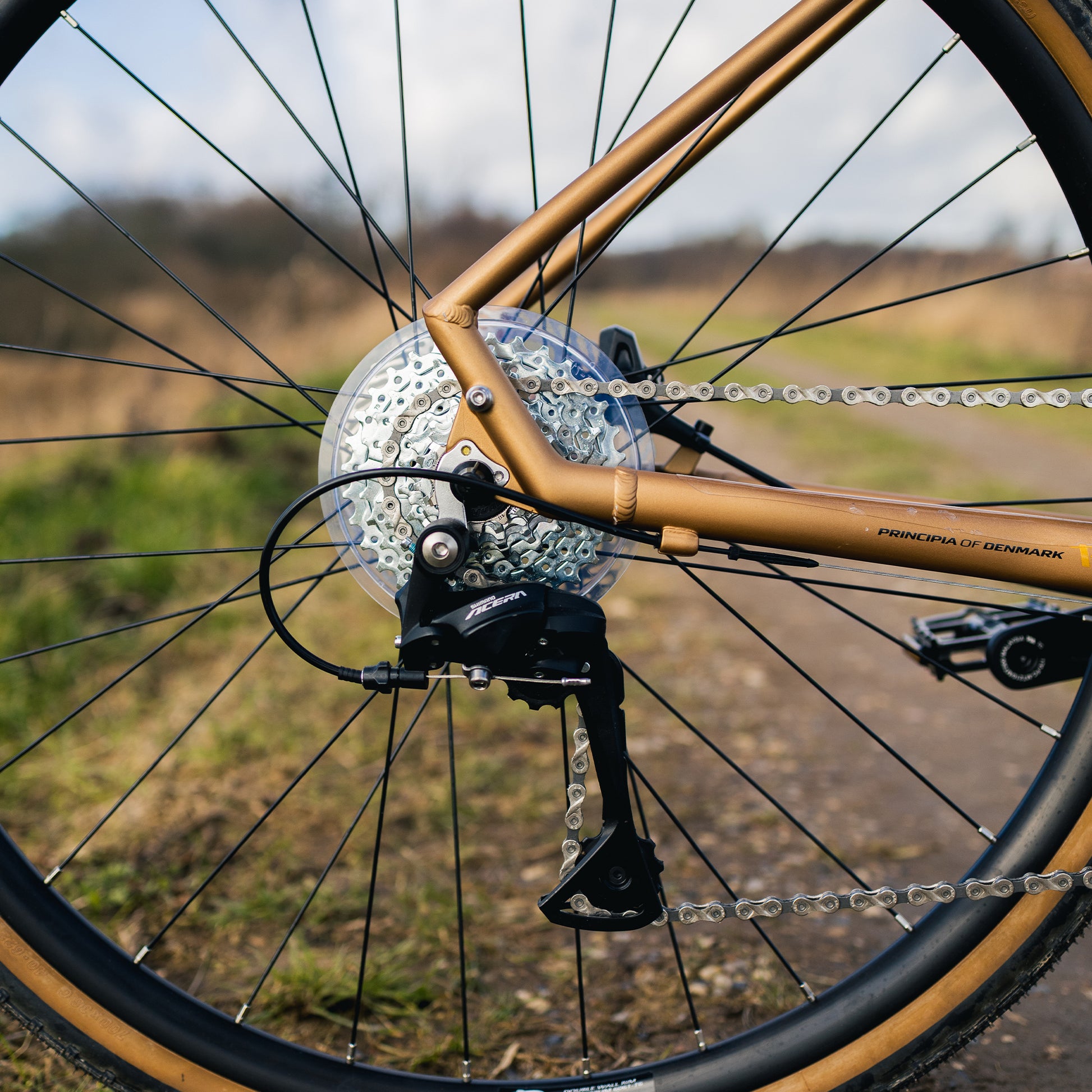 Kopparfärgad gravelcykel med skivbroms och grusdäck på framhjulet, detalj.