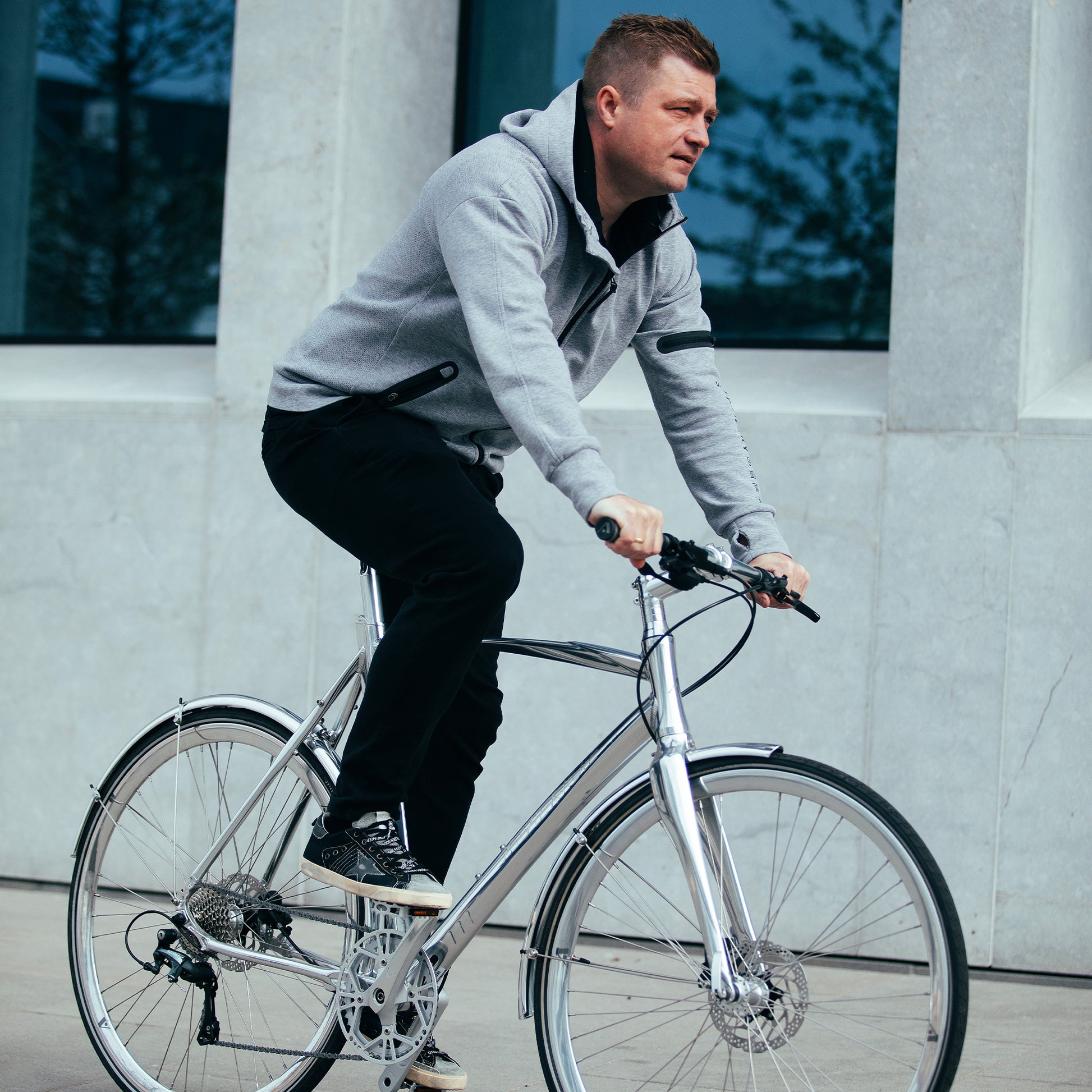 Metallcykel i blank silver med styre och sadel, användare i förarställning