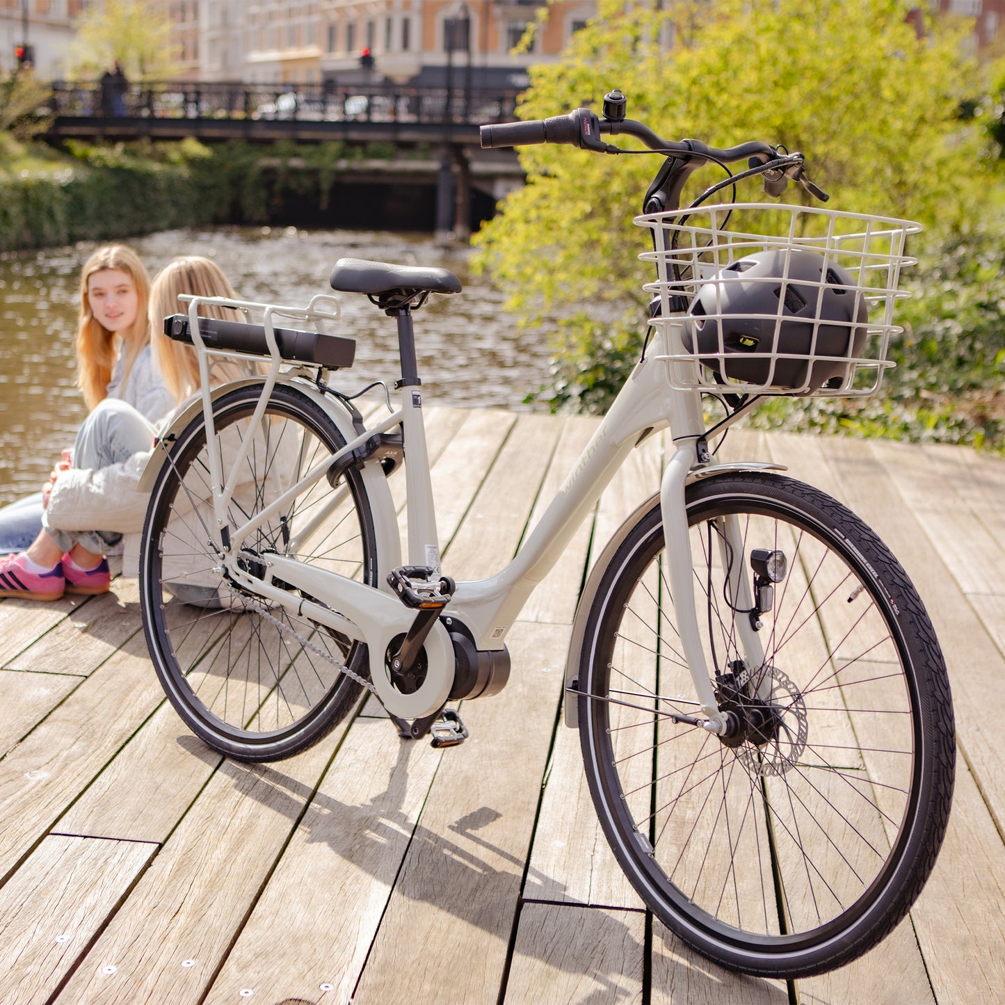 Ljusgrå damcykel med frontkorg och pakethållare