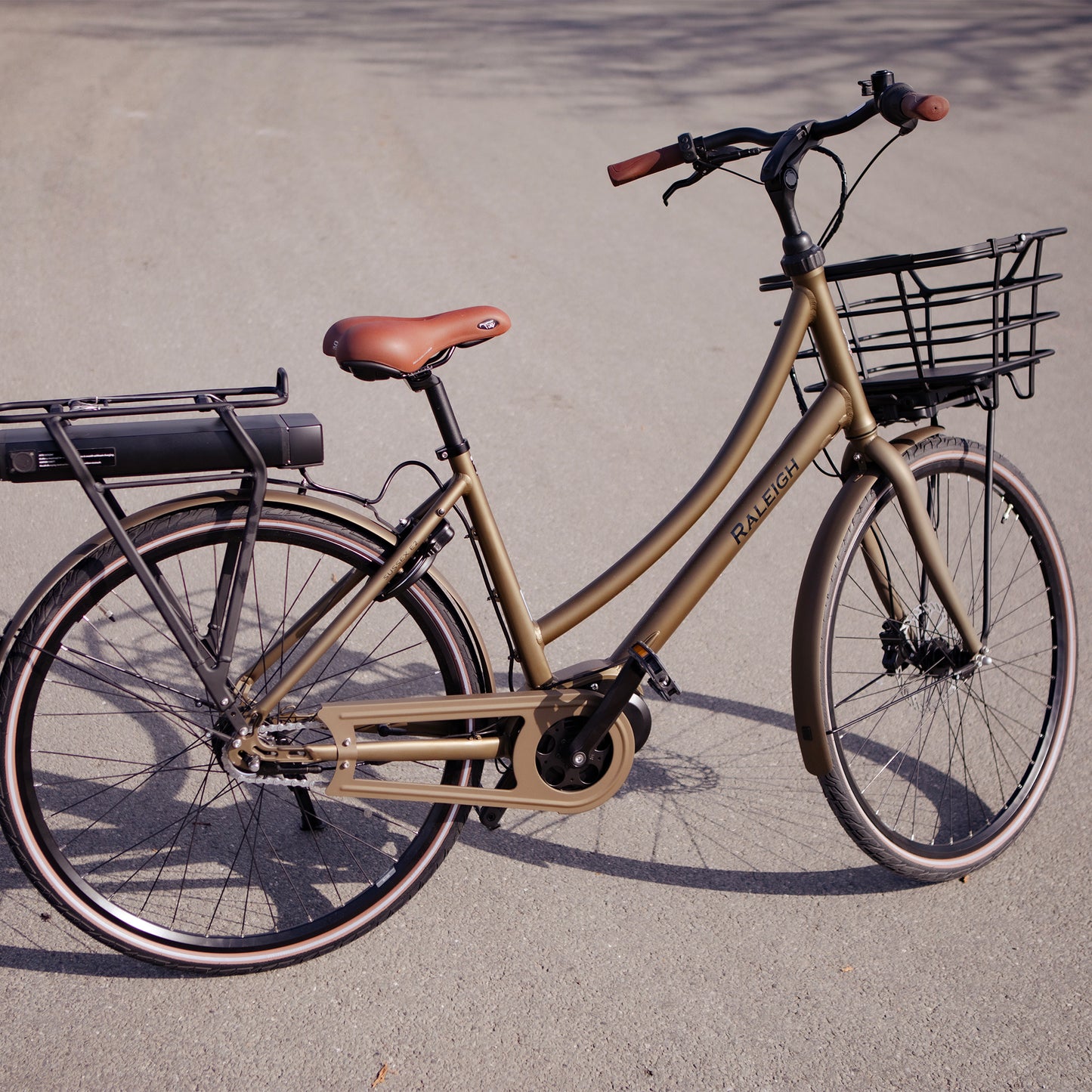 Raleigh Sussex E2 elcykel i matt sand, sidovy med främre korg och belysning